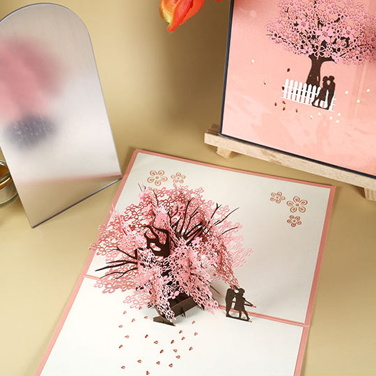 Biglietto d'auguri pop-up 3D con coppia romantica sotto un ciliegio